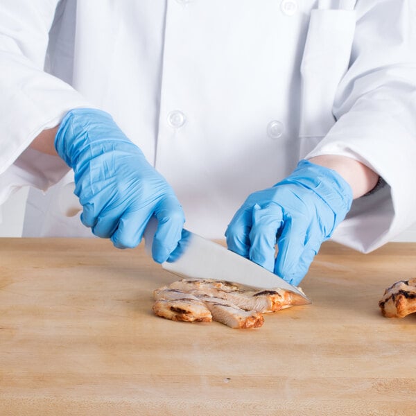 A person in blue gloves using a Choice chef knife to cut meat.