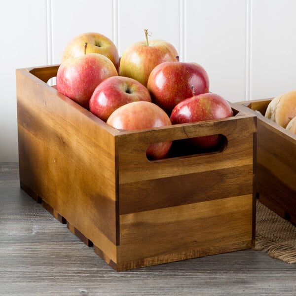 A Tablecraft acacia wood crate full of apples on a table.