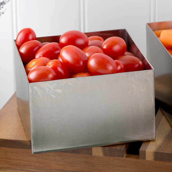 Two Tablecraft stainless steel square bowls filled with tomatoes on a counter in a salad bar.