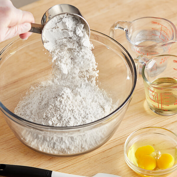 A person pouring ADM All Purpose Unbleached Flour into a bowl.