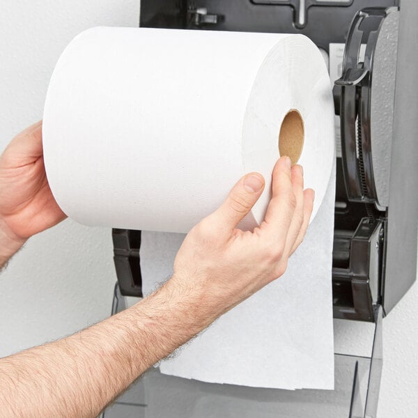A person holding a Lavex white hardwound paper towel roll in front of a white background.