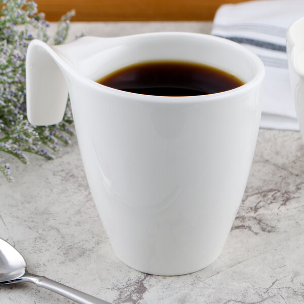 A Villeroy & Boch white porcelain mug with a handle filled with coffee on a saucer.