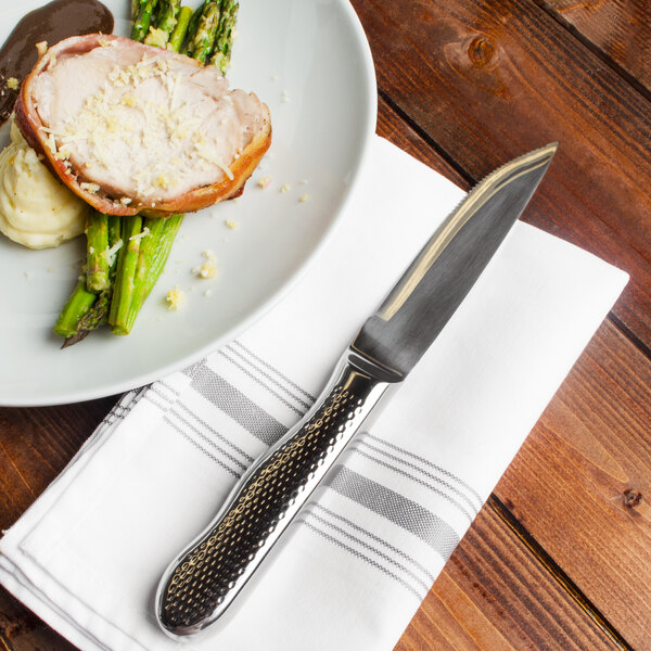 A plate of food with a Walco Ironstone steak knife on a napkin.