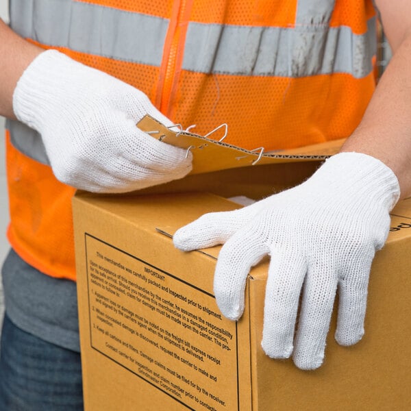 A person wearing Cordova white work gloves holding a box.