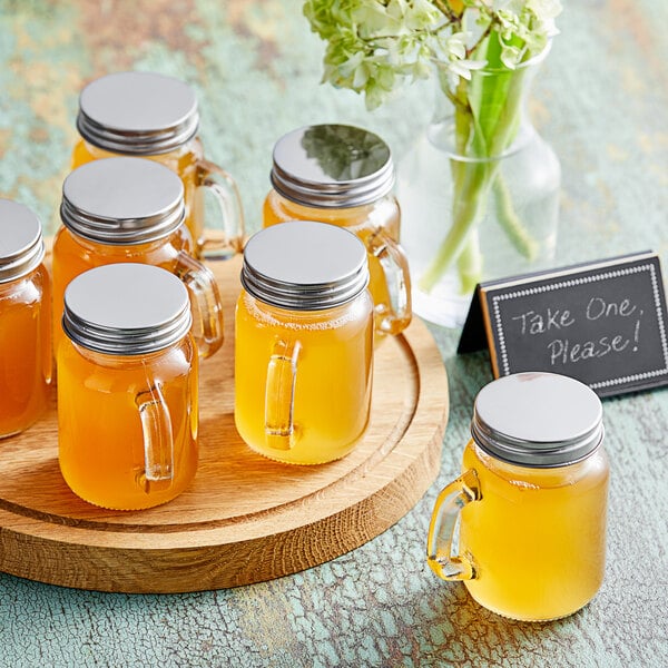 A wooden tray with Acopa Rustic Charm mini mason jars filled with yellow liquid and flowers.