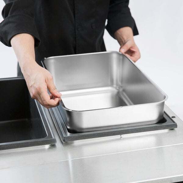 A person holding a Choice stainless steel steam table spillage pan.