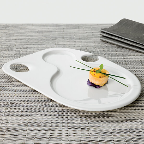 A Villeroy & Boch white porcelain bento party plate on a table with food.