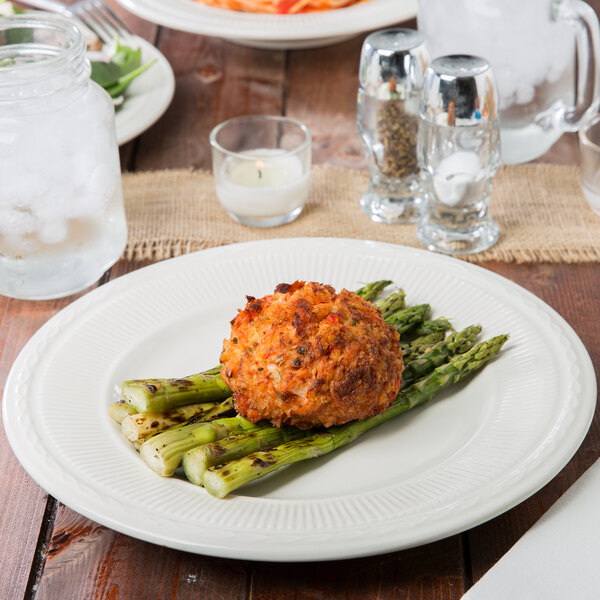 A plate of asparagus and meatballs on an ivory embossed rim china plate.