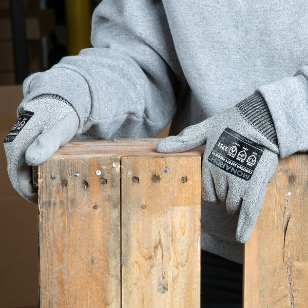 A person wearing Cordova Monarch gray cut resistant gloves holding a piece of wood.