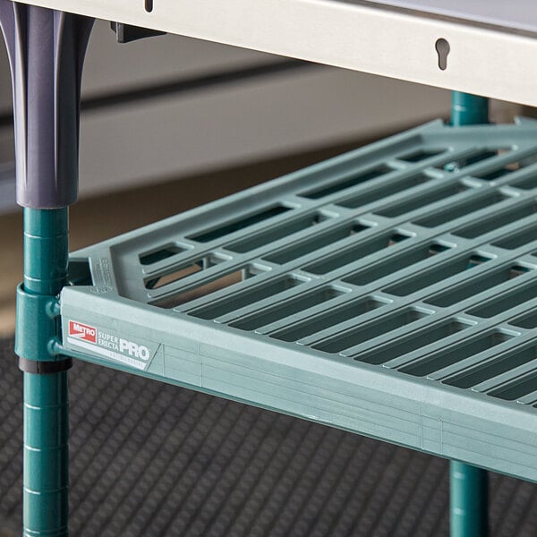 A green Metro Super Erecta Pro shelf on a metal frame over a table.