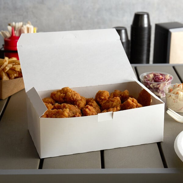 A white take out box of fried chicken on a table.