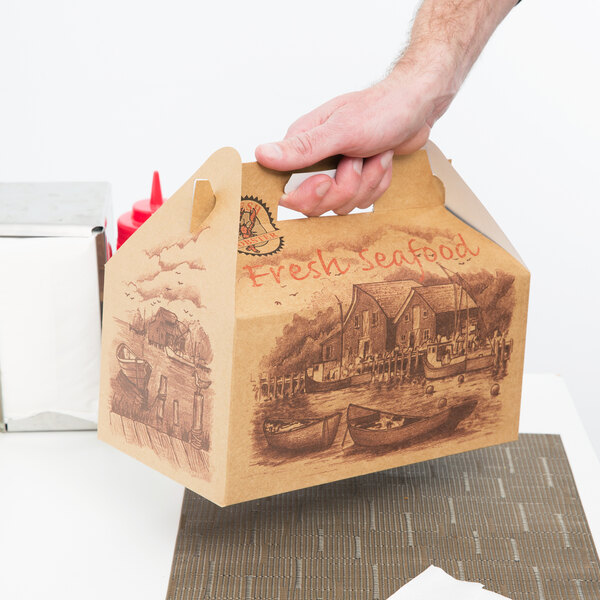 A hand holding a Fresh Seafood Barn take-out box with a handle.