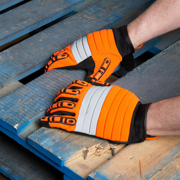 A person wearing Cordova Hi-Vis orange and black warehouse gloves.