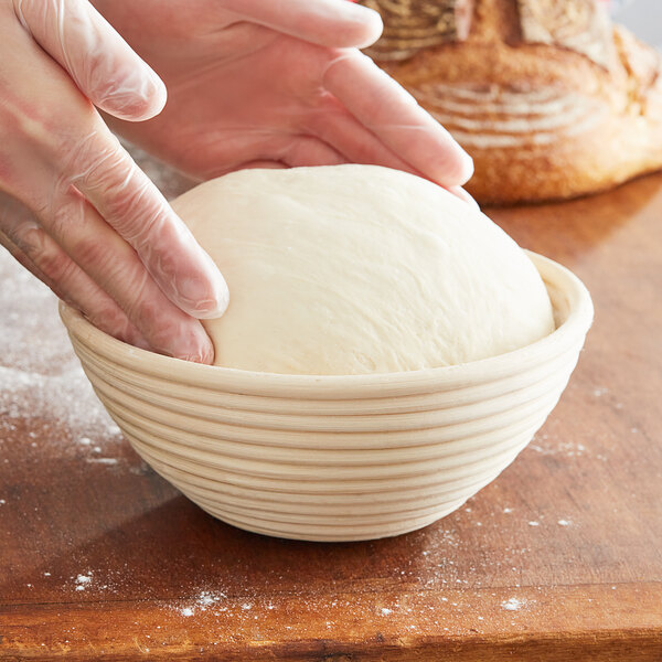 A person kneading dough in a Matfer Bourgeat round willow proofing basket.