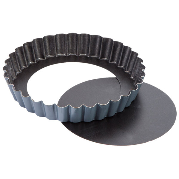 A black Matfer Bourgeat round metal tart pan with a circular design on the bottom.