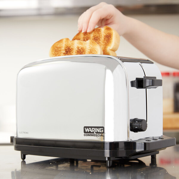 A person toasting bread in a Waring commercial toaster.