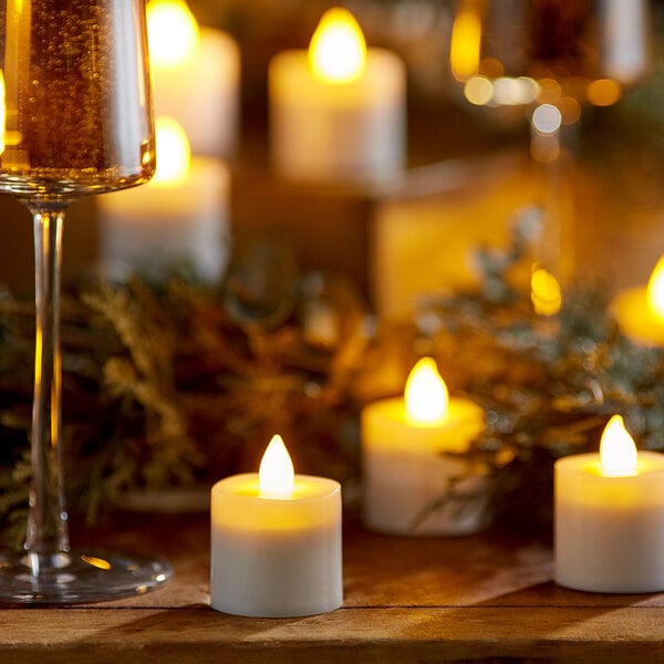A group of lit Sterno amber flameless tea lights on a table next to wine glasses.