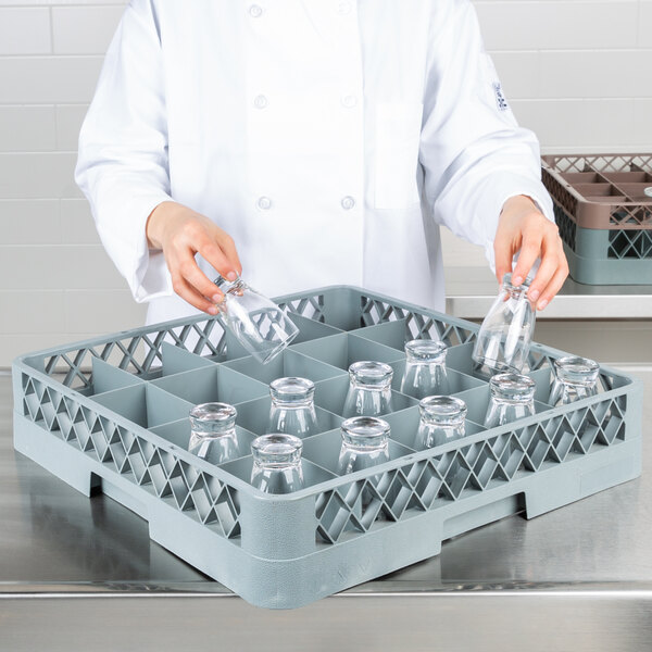 A person in a white coat using a Noble Products full-size glass rack to wash glasses.