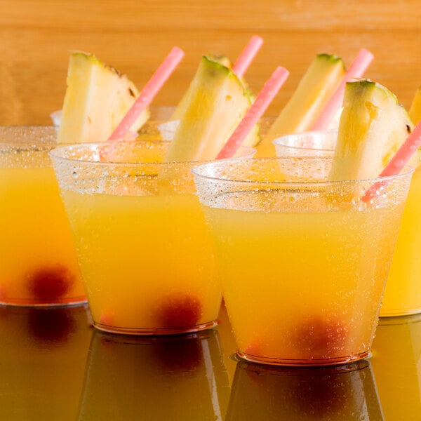 A group of glasses of Narvon pineapple juice with fruit in them.