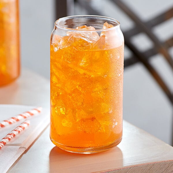 A glass of Narvon orange soda with ice and a straw.