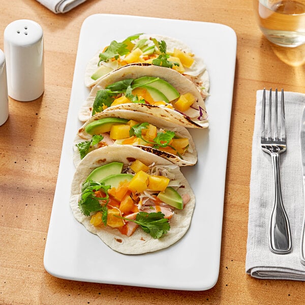 An Acopa rectangular white porcelain plate topped with tacos and a fork.