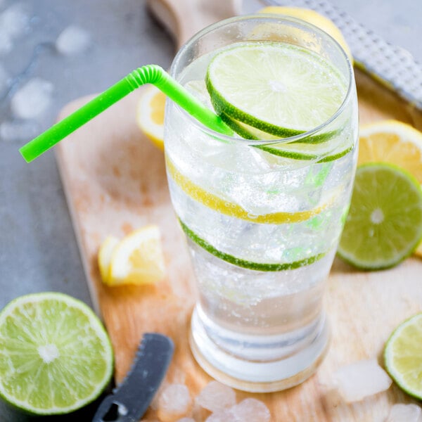 A glass of water with a lime wedge and a straw.