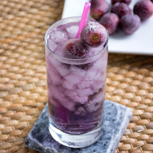 A glass of Narvon grape soda with ice and fruit.