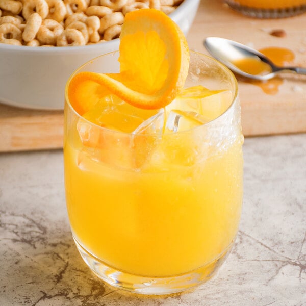 A glass of Narvon orange juice with a slice of orange on top of it.