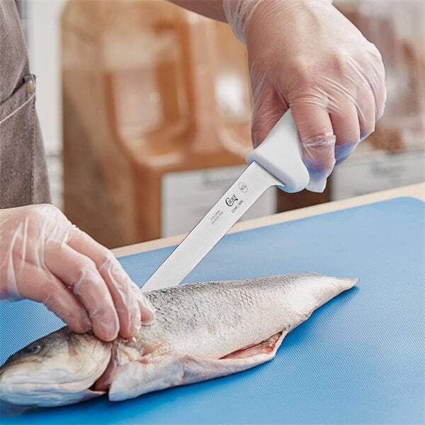 A person using a Choice Narrow Semi-Stiff Fillet Knife with a white handle to cut a fish.
