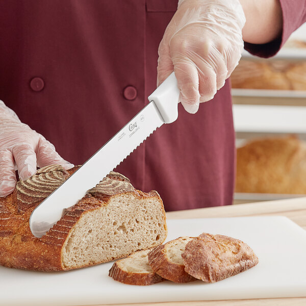 A person using a Choice serrated bread knife to slice a loaf of bread.