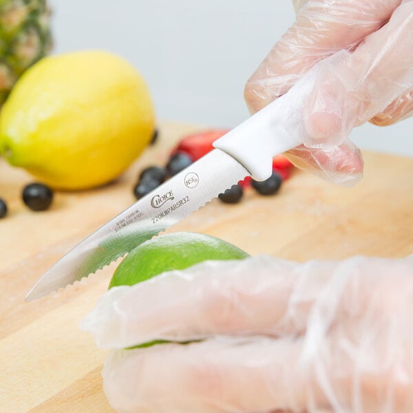A person using a Choice serrated edge paring knife to cut a lime.