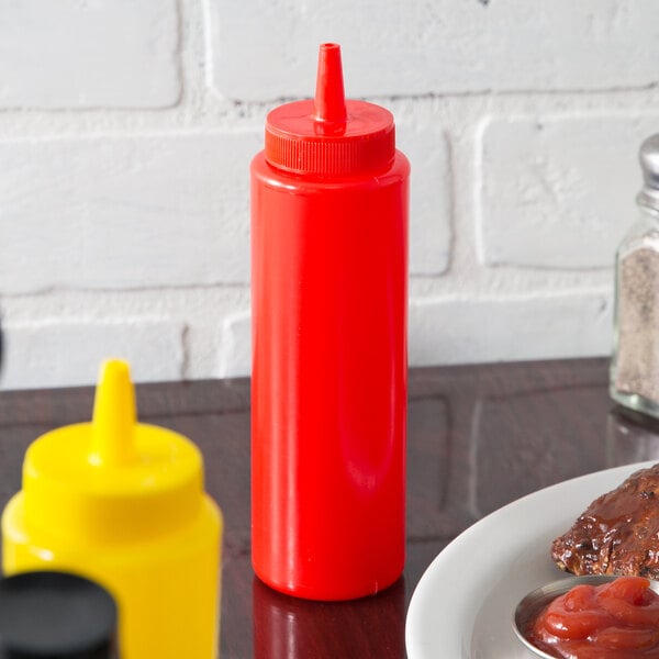 A red Choice squeeze bottle next to a yellow squeeze bottle on a table with a plate of steak.