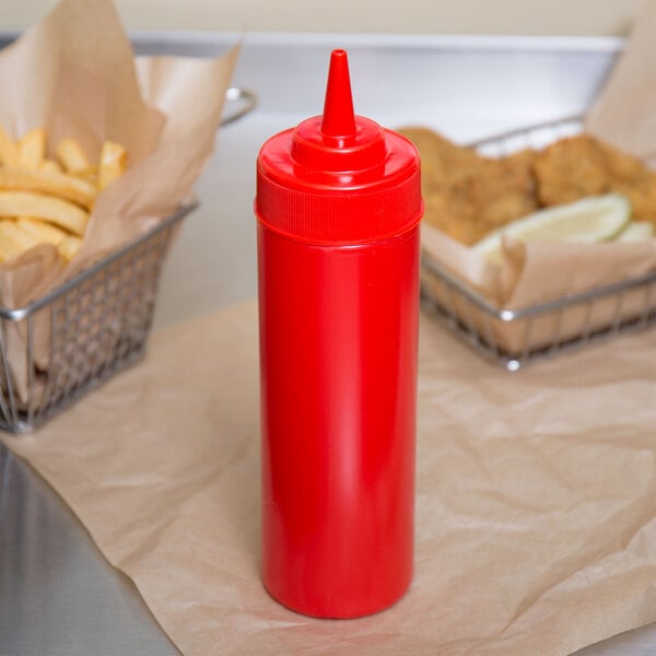 A red Choice wide mouth squeeze bottle on a table next to french fries.
