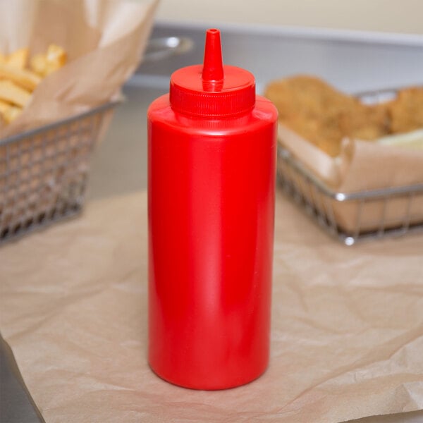 A red Choice squeeze bottle of ketchup on a table with french fries.