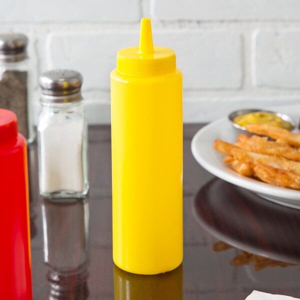 A yellow Choice squeeze bottle next to a plate of fries with a small bowl of mustard.