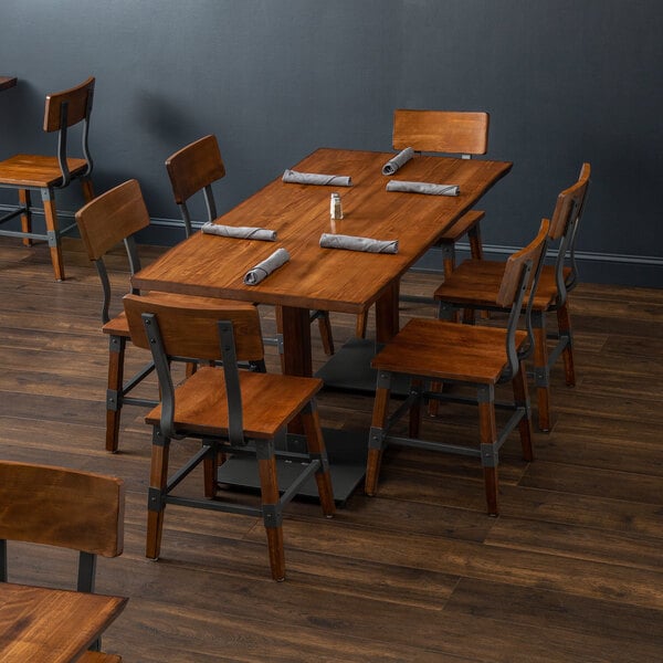 A Lancaster Table & Seating solid wood live edge dining table with chairs and napkins in a restaurant dining area.