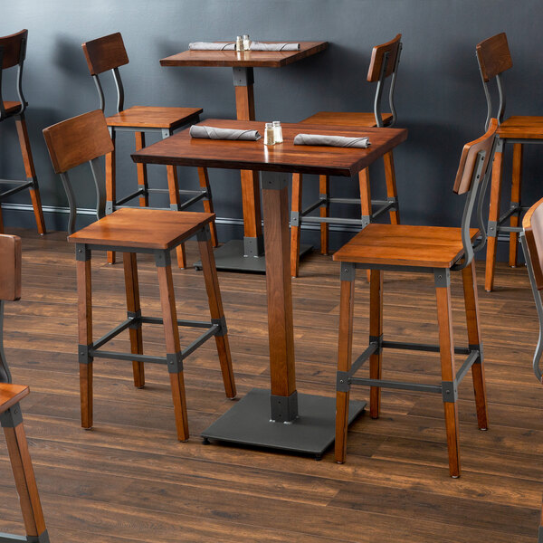 A Lancaster Table & Seating live edge bar height table with wooden bar chairs.