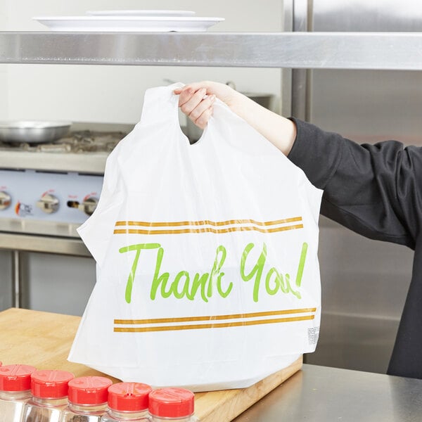 A woman holding a white plastic "Thank You" bag with wave handles.