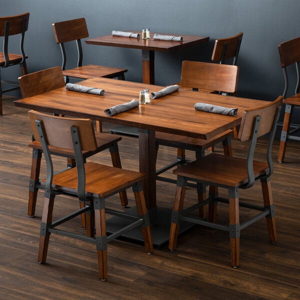 A Lancaster Table & Seating wood table and chair set with napkins on it.