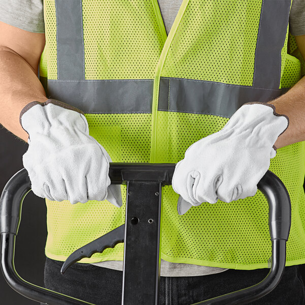 A man wearing Cordova gray leather driver's gloves holding a black and white tool.