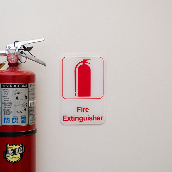 A Thunder Group fire extinguisher sign next to a fire extinguisher on a wall.
