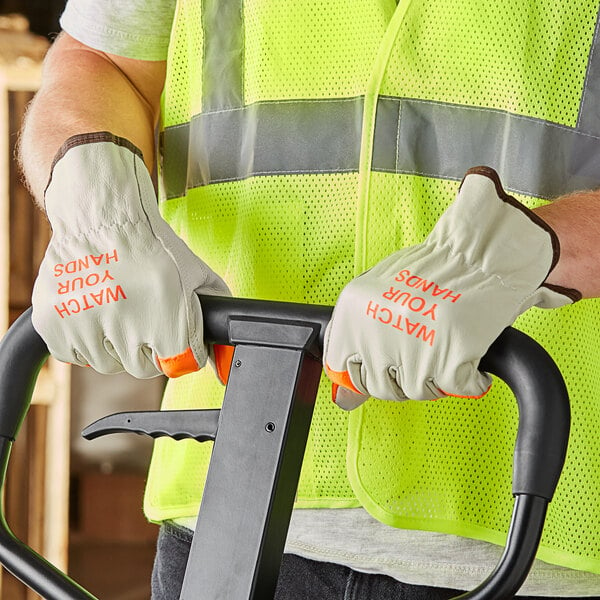 A person wearing Cordova standard grain leather driver's gloves with Hi-Vis orange fingertips.