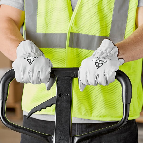 A man wearing Cordova premium goatskin driver's gloves standing next to a forklift.