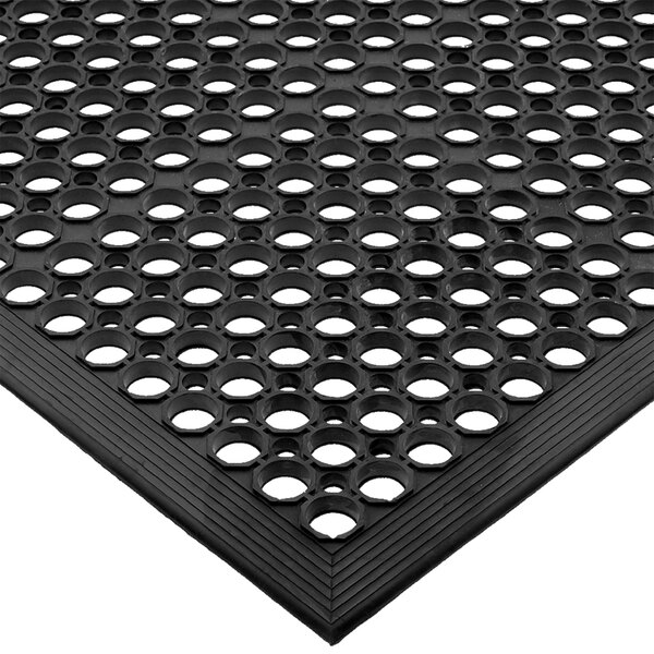 A close-up of a black San Jamar rubber floor mat with holes.