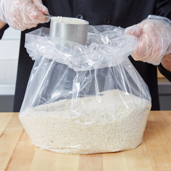 A person in gloves using a LK Packaging plastic food bag to fill a container with rice.