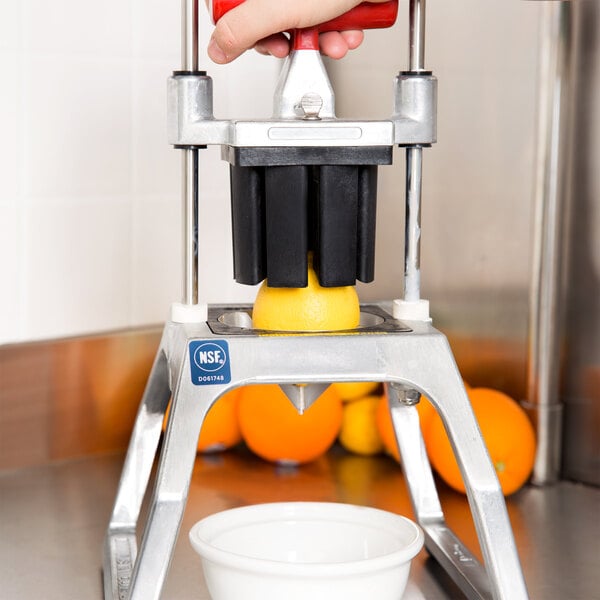 A person using a Vollrath InstaCut 3.5 tabletop fruit and vegetable wedger to cut a lemon.