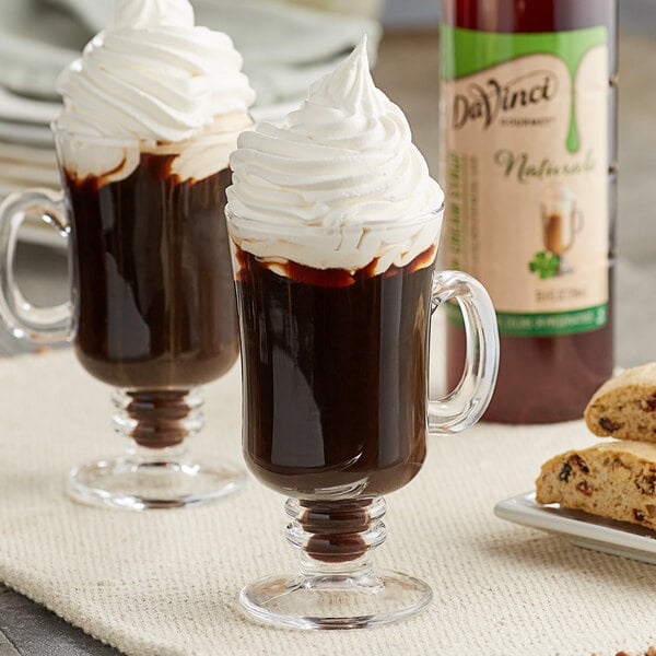 Two glass mugs of DaVinci Gourmet Irish Cream hot chocolate with whipped cream and cookies.