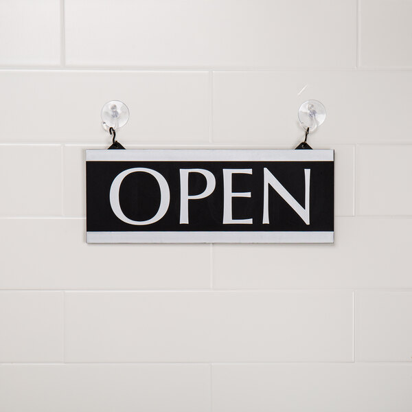 A black and white Headline Sign that says "Open" on a wall.