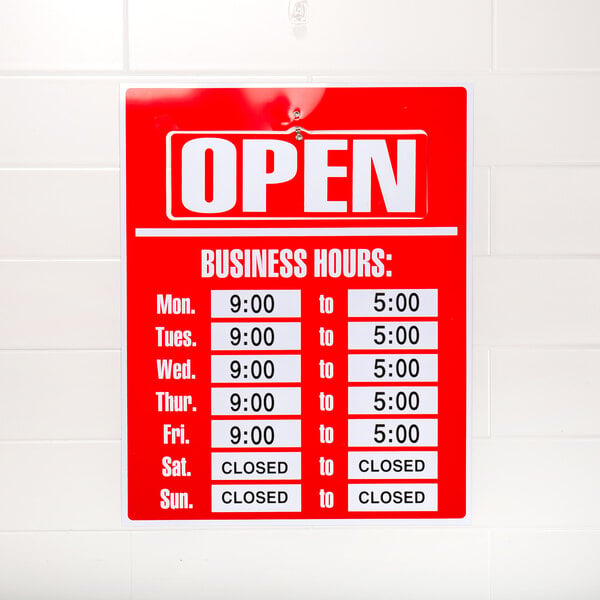 A red and white Cosco business hours sign with black numbers on a wall.