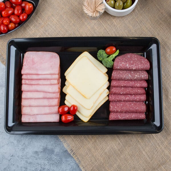 A Fineline black plastic rectangular catering tray with sliced meat, cheese, and tomatoes.